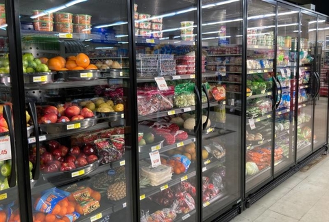 Row of new refrigerators filled with grocery store items.