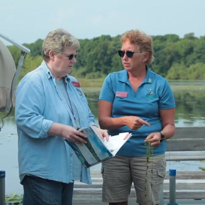 Two women standing on a dock talking.