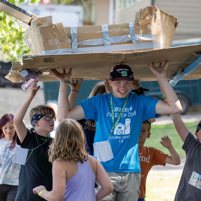 Seven youth march their cardboard boat toward the water to see if it will float