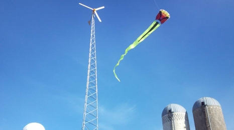 Kite and wind turbine with a bright blue sky