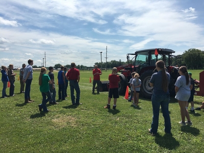 instructor with a group of youth and a tractor
